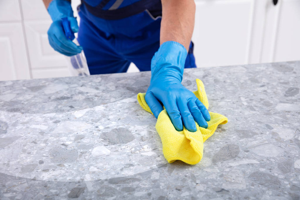 Mid Section Of A Male Janitor Cleaning Dirty Kitchen Counter With Spray Bottle And Napkin - Photo, Image