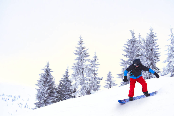 Snowboarder Riding Snowboard in the Beautiful Mountains. Snowboarding and Winter Sports Concept - Foto, Imagem