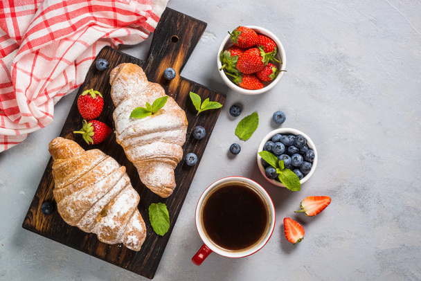 Croissant mit frischen Beeren und einer Tasse Kaffee. - Foto, Bild