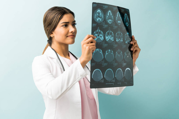 Красивая женщина-врач осматривает рентген, стоя в студии
 - Фото, изображение