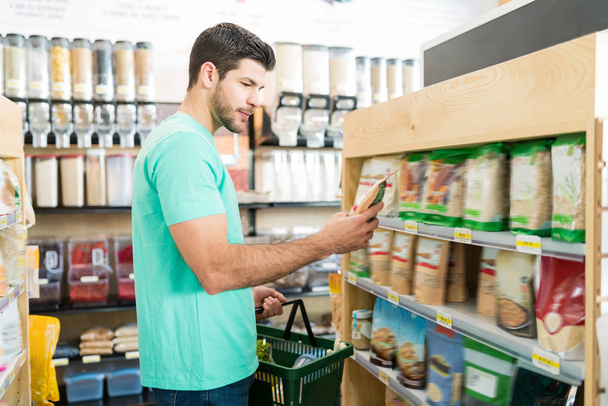 Side näkymä komea Latinalaisen mies ostaa ruokaa supermarketista
 - Valokuva, kuva
