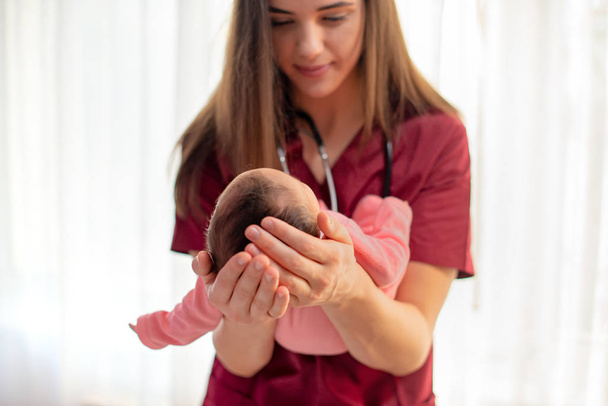 Педиатр держит красивую новорожденную девочку
 - Фото, изображение