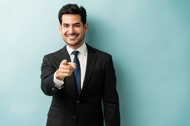 Confident good looking young businessman pointing finger while standing against isolated background - Foto, immagini