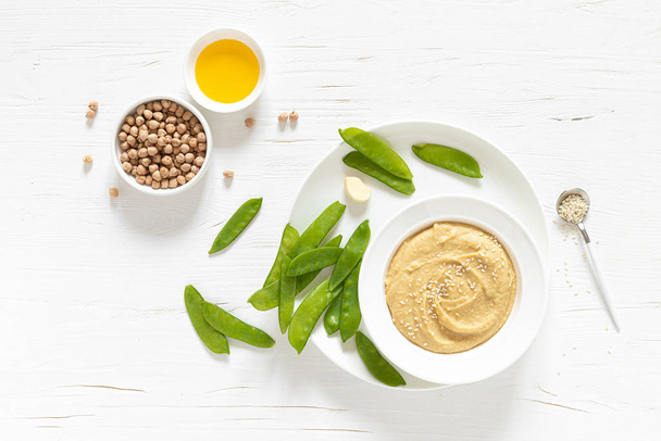 Homemade chickpea hummus served with green peas, healthy vegetarian food concept, top view - Foto, Imagem