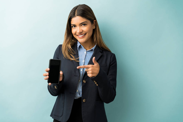 Bello sguardo giovane dirigente femminile che punta al telefono cellulare mentre in piedi in studio
 - Foto, immagini