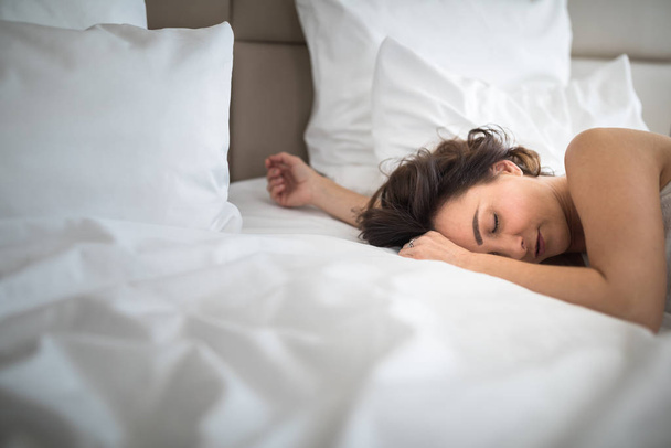 Beautiful young woman sleeping on bed at bedroom - Fotó, kép
