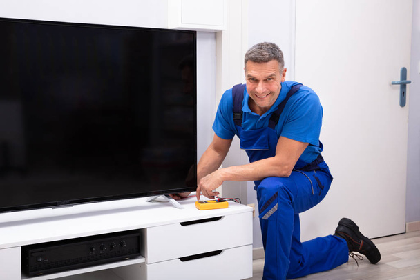 Mature Male Technician Repairing Television With Digital Multimeter - Photo, Image