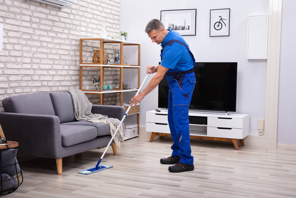Mature Male Janitor Cleaning Floor With Mop At Home - Fotó, kép
