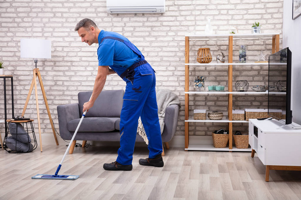 Mature Male Janitor Cleaning Floor With Mop At Home - Foto, Imagem