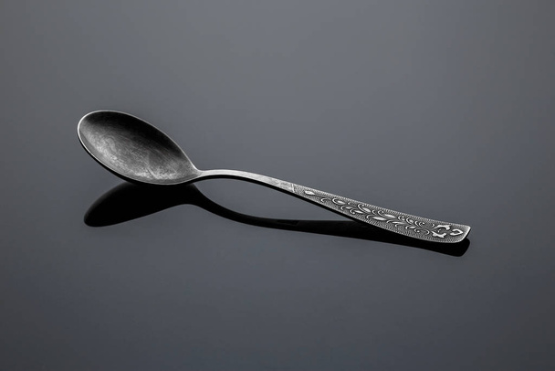Old nickel silver spoon on a reflective surface - Φωτογραφία, εικόνα