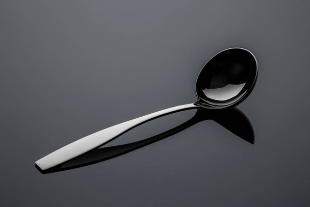 Stainless steel metal spoon on a reflective surface - Foto, Imagem