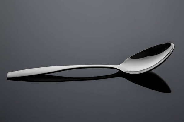 Stainless steel metal spoon on a reflective surface - Fotó, kép