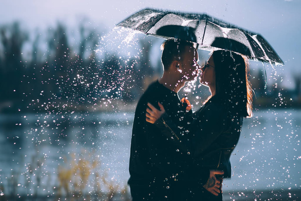 young couple standing under a dark umbrella. - Foto, Imagen