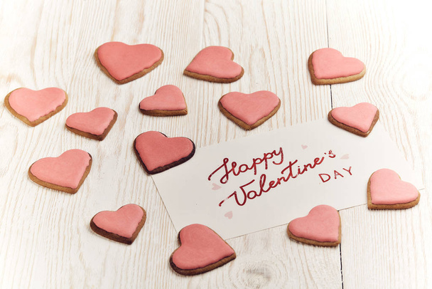 Cookies in the form of heart and greeting card  lying on a light wooden background. Valentine's Day card, - Foto, Imagem