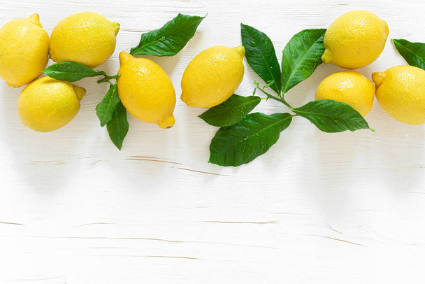 Fresh lemons with leaves on white wooden background,  summer lemonade ingredient, vitamin c concept, top vie - Foto, Bild