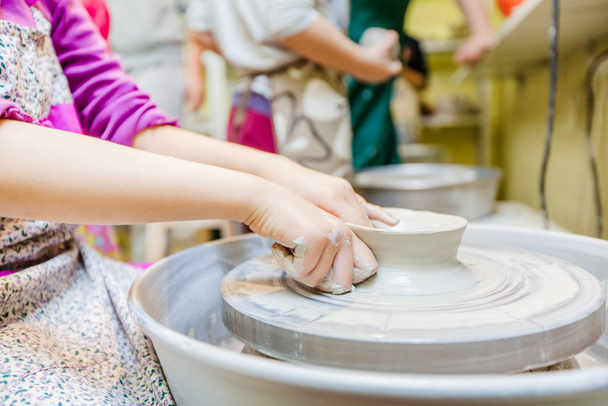 Pottery workshop for children - Child hands shaping clay at wheel - Foto, Bild