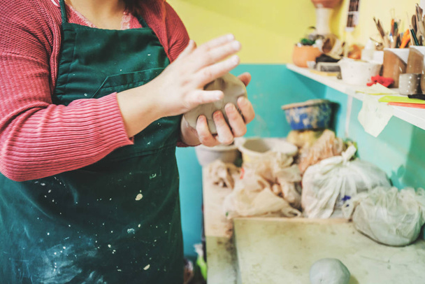 Female potter hands molding clay on table at pottery workshop. - Fotoğraf, Görsel