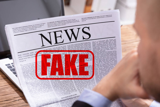 Man Reading Fake News In Newspaper Over Desk - Fotoğraf, Görsel