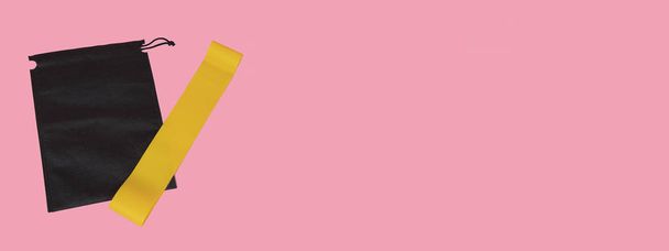 Sports yellow elastic band . Sports equipment, sports at home, article about sports, equipment for home sports. Yellow rubber band on a pink background. - Fotó, kép