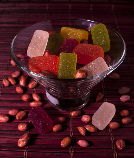 Sweets in glassware on a bamboo napkin. Multicolored jelly candies and peanuts - 写真・画像