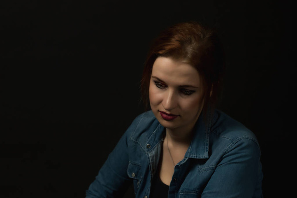 Low key portrait of sad young woman on the black background. - Photo, image