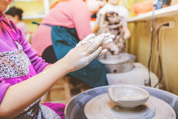 Child hands shaping clay on pottery wheel at workshop. - Valokuva, kuva