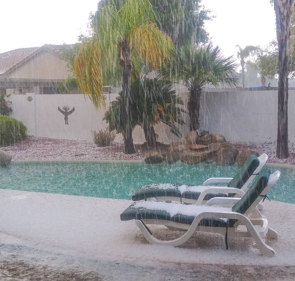 Heftiger Hagelsturm bedeckt Liegestühle und Boden. Es plätschert auch in den Pool. in glendale, maricopa county, arizona usa - Foto, Bild