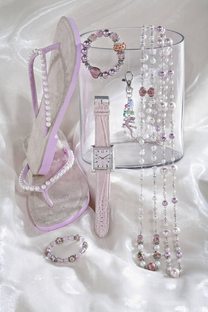 still life of pink necklace chains watch and flip flops on white satin background - Zdjęcie, obraz