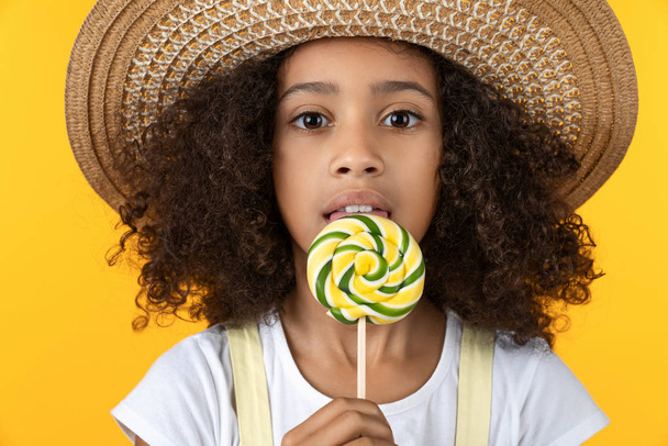 Close up of funny child with candy lollipop isolated on yellow background - Photo, image