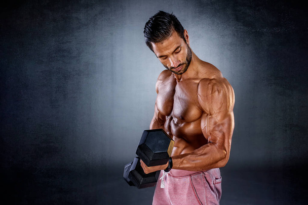 Ejercicio fuerte de los hombres musculares con pesas. Culturista haciendo mancuerna bíceps rizos
 - Foto, imagen
