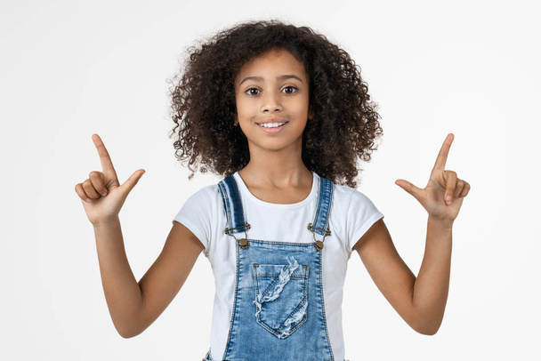 Happy african american girl pointing fingers at copy space isolated over white background - Foto, imagen