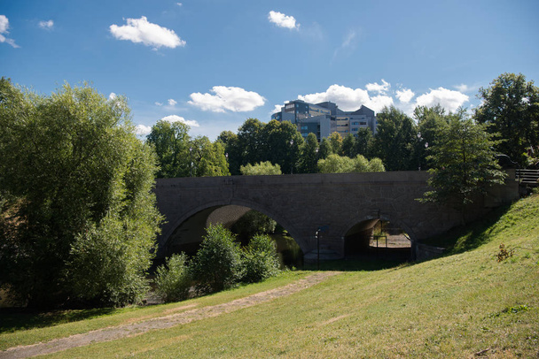 hermoso puente viejo a través del río, plantas verdes y edificios modernos detrás en oslo, norway
  - Foto, Imagen