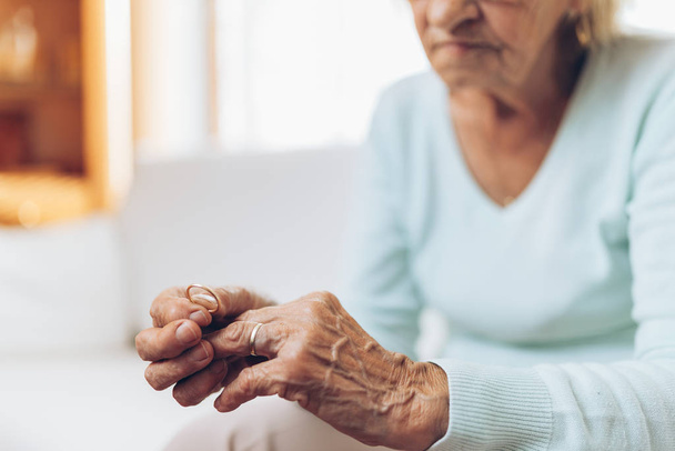Heartbroken elderly woman holding he husbands wedding ring - Photo, Image