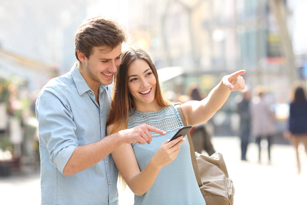 Happy friends or couple checking location on smart phone in the street - Φωτογραφία, εικόνα
