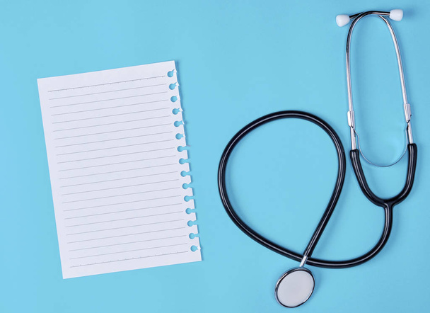 white piece of paper in a line and a medical stethoscope on a blue background - Photo, Image