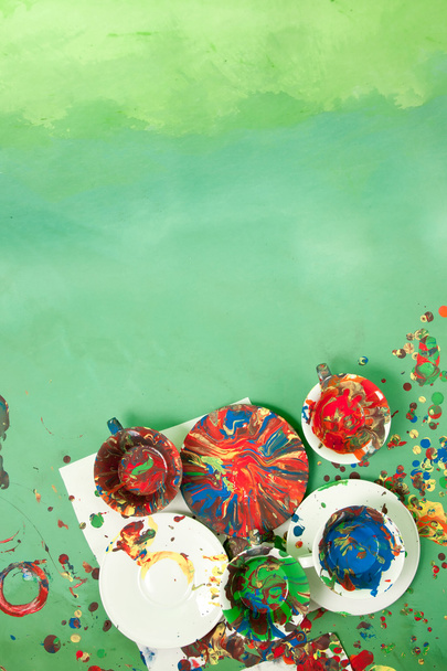 Tarjeta con tazas con platillos llenos de pinturas brillantes sobre un fondo verde
 - Foto, imagen