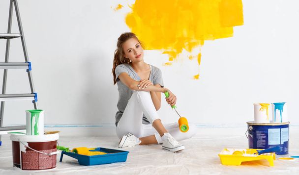 Repair in apartment. Happy young woman paints wall  - Fotografie, Obrázek