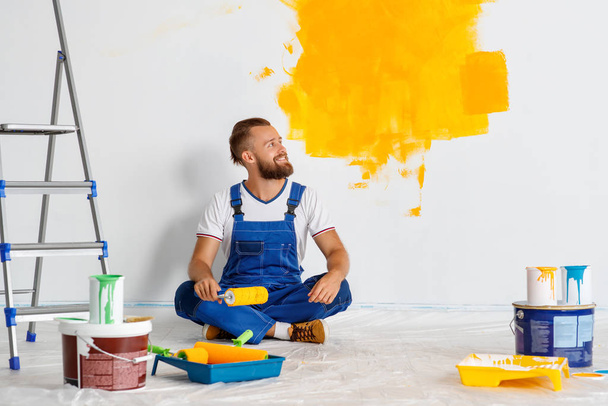 Repair in apartment. Happy man worker paints wall - Φωτογραφία, εικόνα