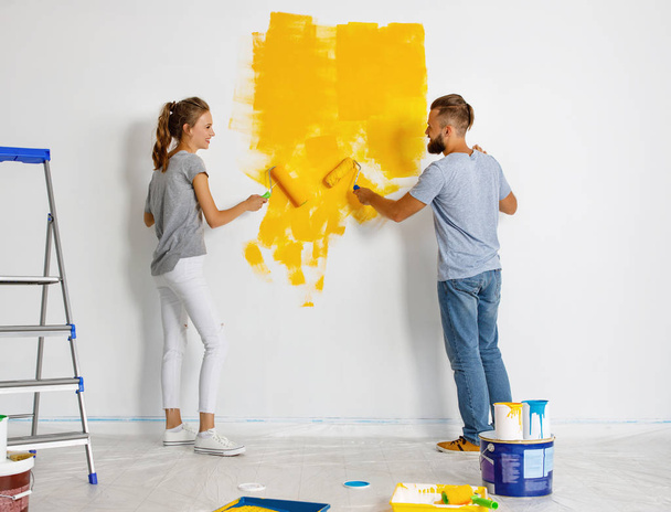 młoda szczęśliwa para naprawia i maluje ścianę w hom - Zdjęcie, obraz
