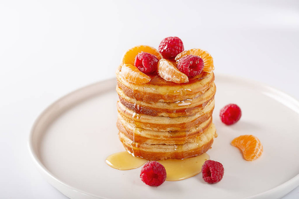 American Sweet homemade stack of pancakes or fritters with raspberry fruits and honey, delicious dessert for breakfast, on white background. selective focus, copy space. - Zdjęcie, obraz