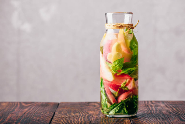 Bottle of Water Infused with Sliced Peach and Basil Leaves. - Фото, изображение