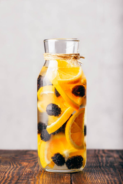 Bottle of Infused Water with Sliced Raw Orange and Fresh Blackberry. - Foto, afbeelding