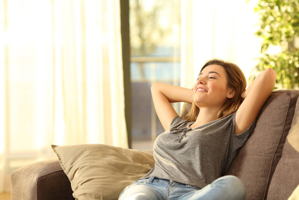 Happy woman resting comfortably sitting on a couch in the living room at home - Foto, Imagem
