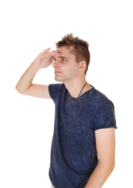 A close up image of a young man in a blue sweater standing with one hand.on his forehead, looking fare away, isolated for white background. - Valokuva, kuva