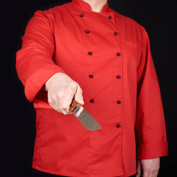 Szef kuchni w czerwonym mundurze trzymając nóż kuchenny w prawej ręce, czarne tło - Zdjęcie, obraz