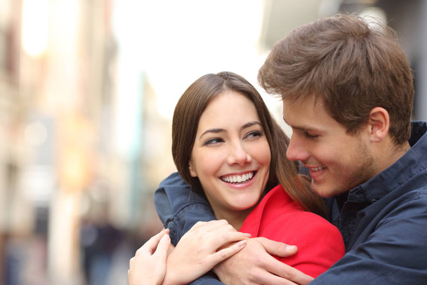 Happy girlfriend with perfect teeth being embraced by her boyfriend in the street - Foto, imagen