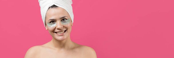 Giovane bella ragazza in un asciugamano bianco sulla sua testa indossa patch di gel di collagene sotto i suoi occhi. Maschera sotto gli occhi trattamento viso. - Foto, immagini