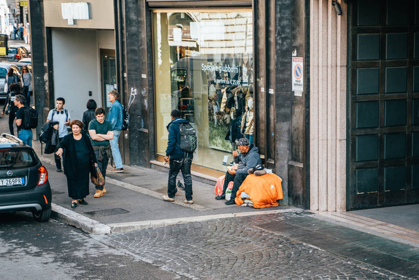 Rome, Italy - October 2019 : Homeless man sitting on Europe street, people pass by, problem of beggars and emigrants without housing in Europe - Zdjęcie, obraz