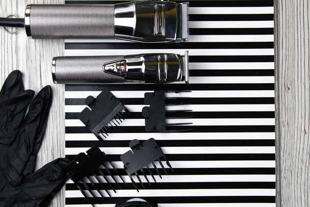 Haircut machines, nozzles of different sizes, combs and gels for styling, laid out on a beautiful black white striped - Photo, image