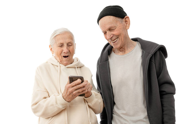 Щаслива зріла пара використовує свій смартфон на білому тлі, стильний старий чоловік і жінка в капюшоні
 - Фото, зображення